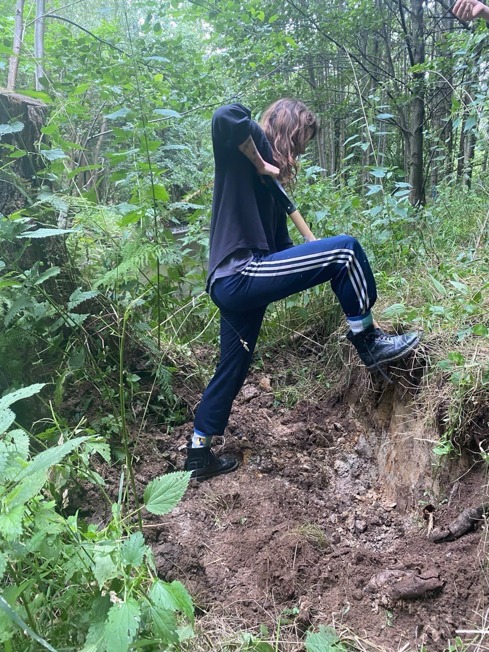 Deborah Geppert gräbt mit einem Spaten Lehm aus einer Böschung in einem sächsischen Wald