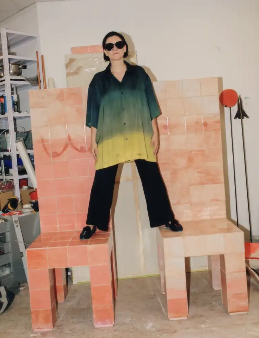 Katja Tönnissen steht im Atelier auf zwei selbstgebauten Stühlen aus rosafarbenen Fliesen