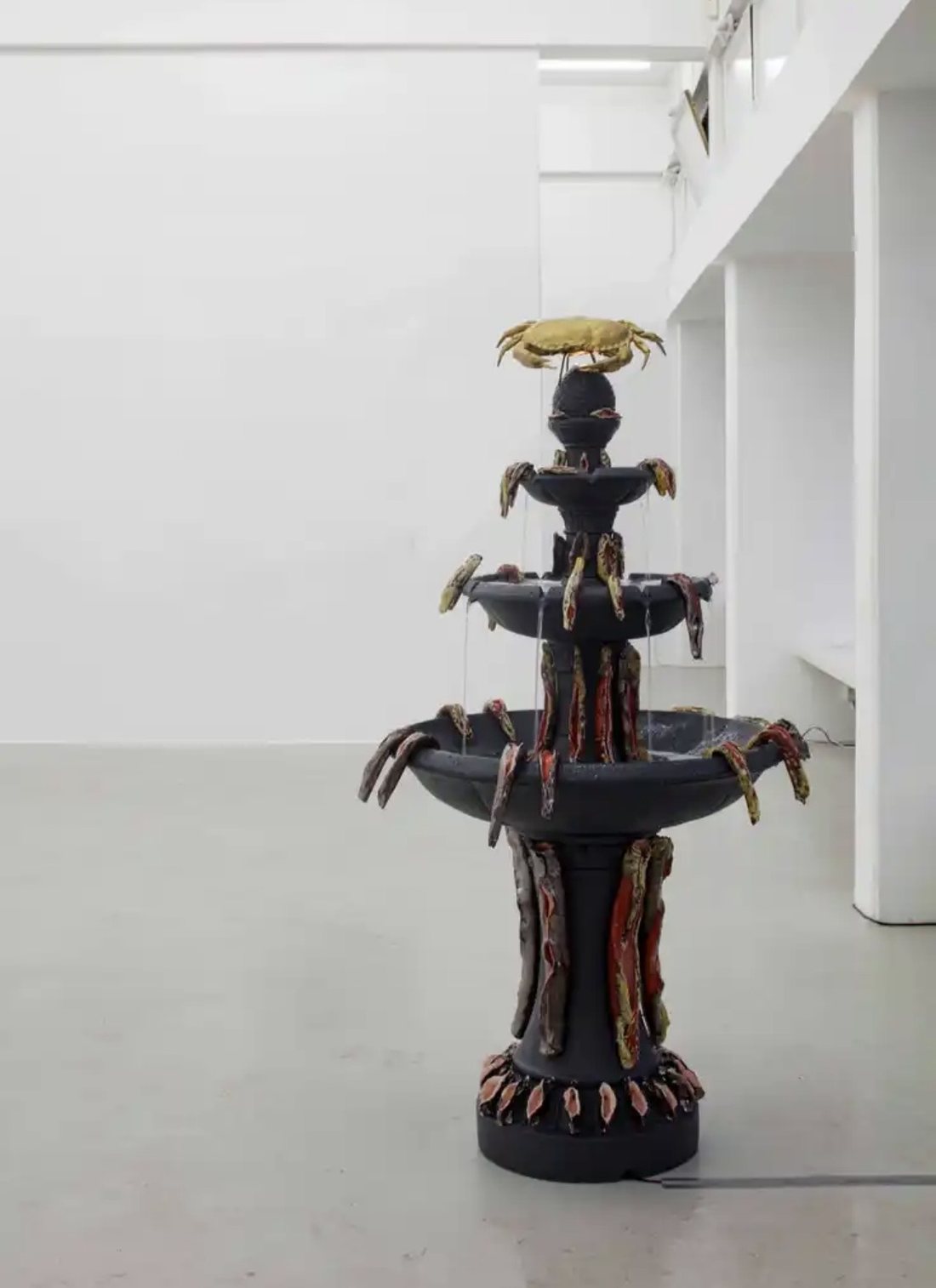Katja Tönnissen, Detox Fountain: dreistöckiger schwarzer Zierbrunnen, besetzt mit keramischen Fischen und einer goldenen Krabbe