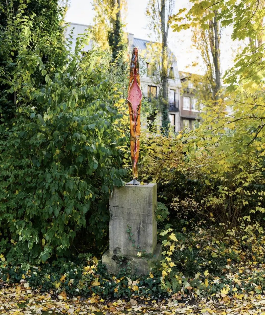 Katja Tönnissen, Venus Capusa II: schlanke Keramikskulptur in Rosa und Orange auf einem alten Steinsockel in einem herbstlichen Garten